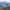 Town nestled in a lush green valley surrounded by forested mountains.