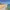 Wide sandy beach with turquoise waves, clear sky, and distant mountains.
