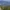 Hiker with a blue backpack overlooks a scenic mountain valley with green trees.
