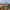 Colorful medieval cityscape with red rooftops, church spires, and lush green trees