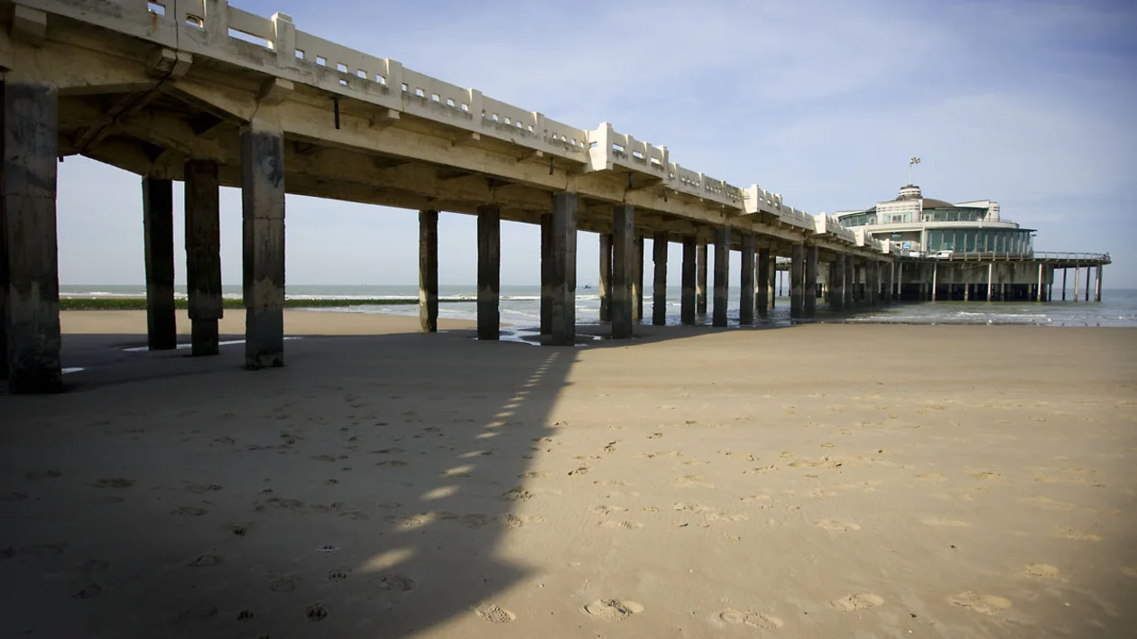 Belgium Pier stretching into the sea, reaching from the shore, its weathered planks extending into the azure expanse.