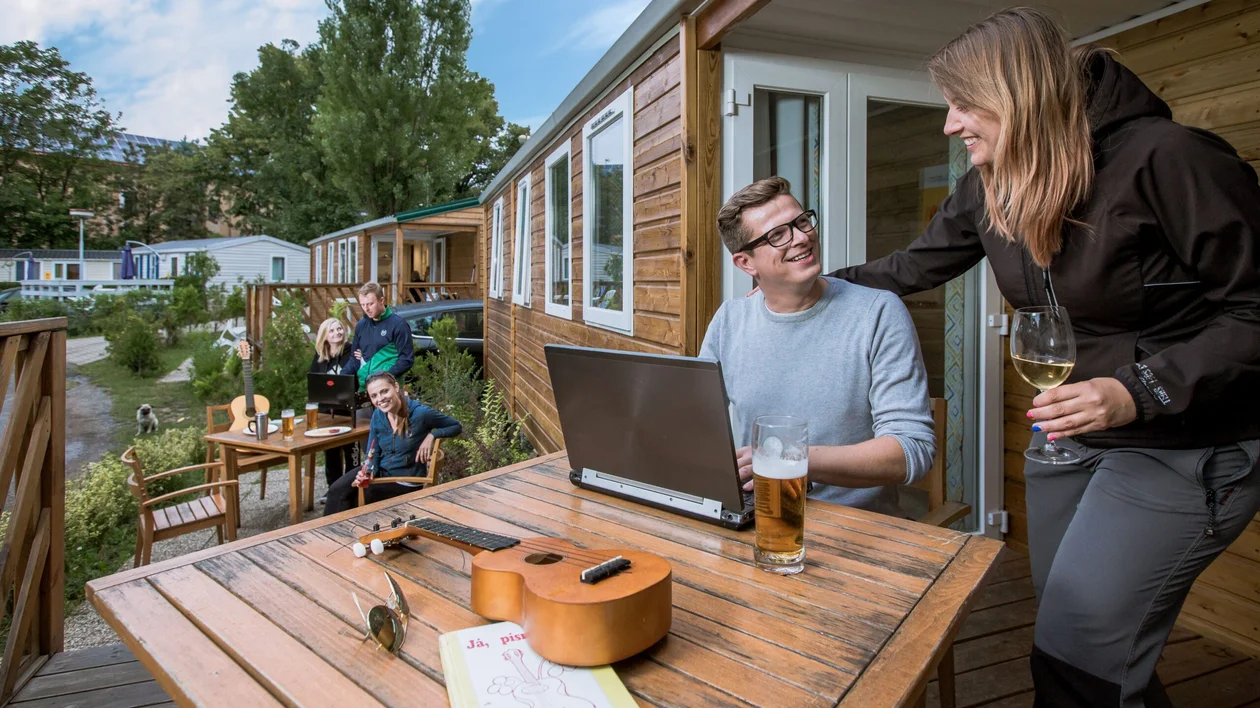 A couple is drinking and working in a camping.