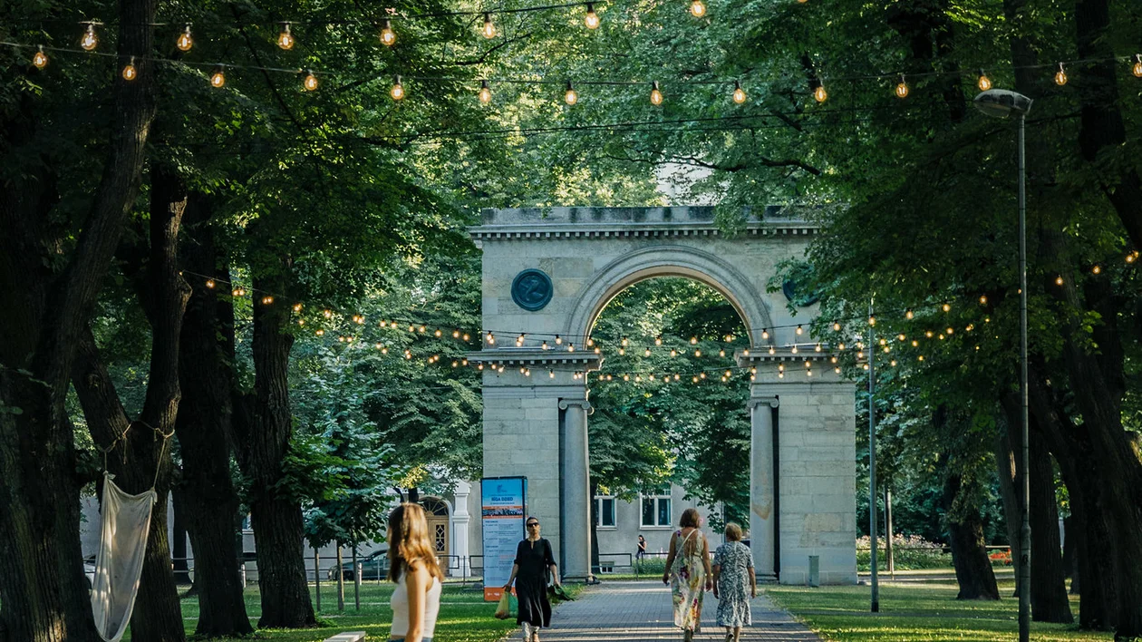 A person walking a dog on a leash at Viesturdārzs Park in summer, Riga.