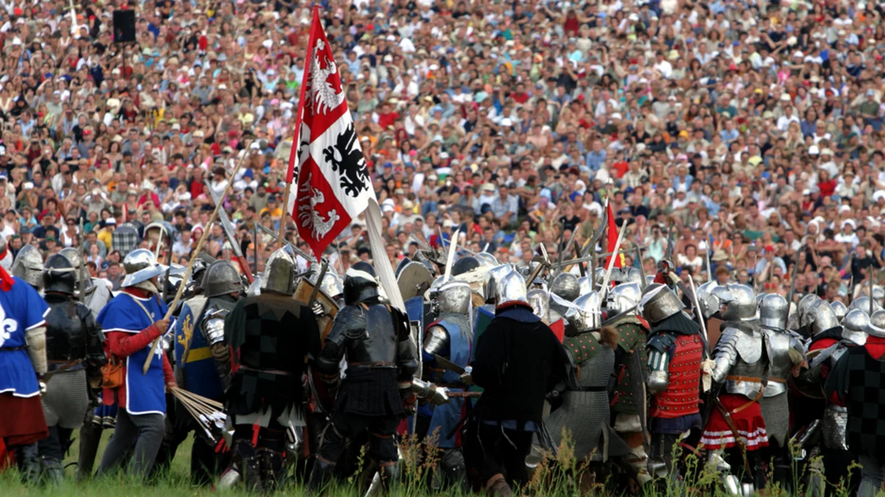 Reenactors dressed as medieval knights before a large crowd on the Battle of Grunwald.