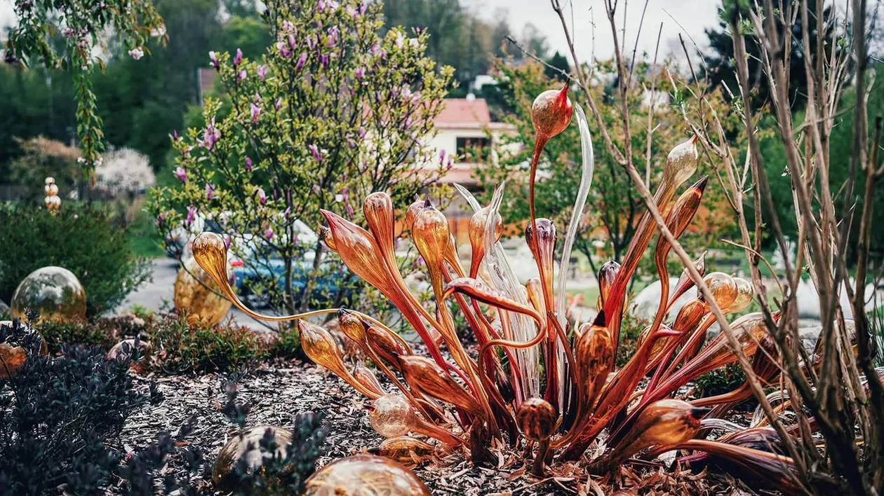 Garden with artistic glass sculptures among living plants.