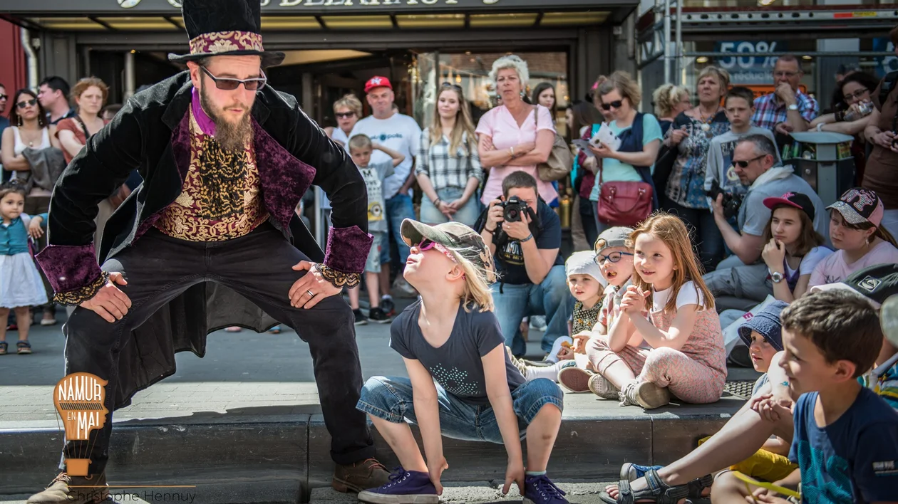 A performer in a top hat and costume entertaining a crowd of onlookers.