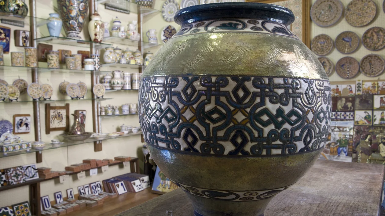 A beautifully designed decorative pot with intricate patterns, displayed in a shop surrounded by various ceramic artworks.