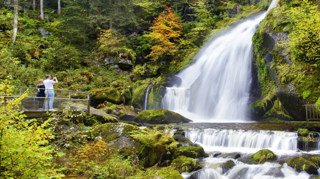 Visitors admiring the cascading Triberg Waterfalls framed by dense forest in the Black Forest, Germany.