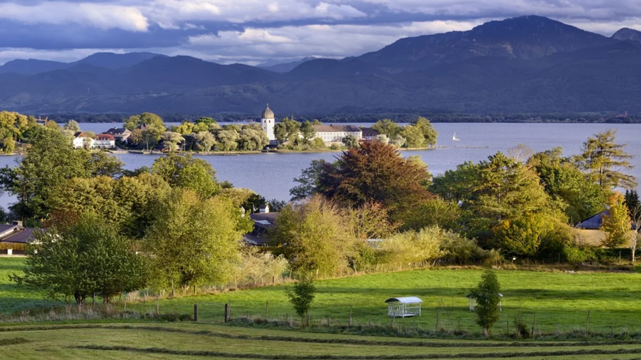 Scenic view of Lake Chiemsee with Frauenchiemsee Island and the Bavarian Alps in the background.