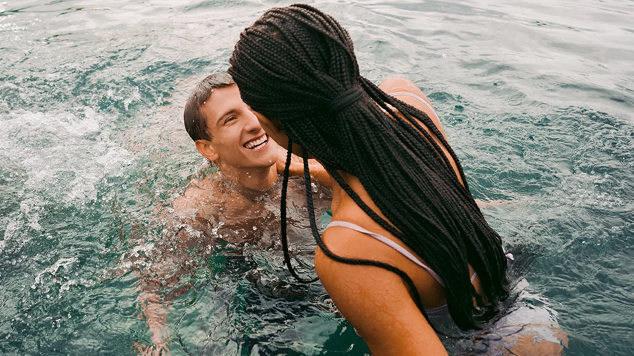 Smiling couple swimming together in a clear alpine lake.