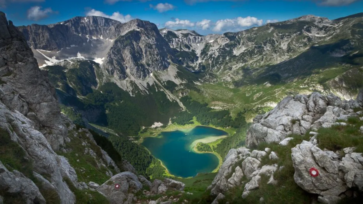 Breathtaking view of Trnovačko Lake, shaped like a heart, surrounded by rugged mountains in Montenegro.
