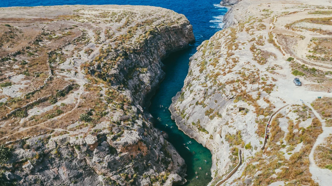Scenic aerial shot of Wied il-Għasri, a narrow and secluded sea inlet flanked by rugged cliffs on Gozo, Malta.