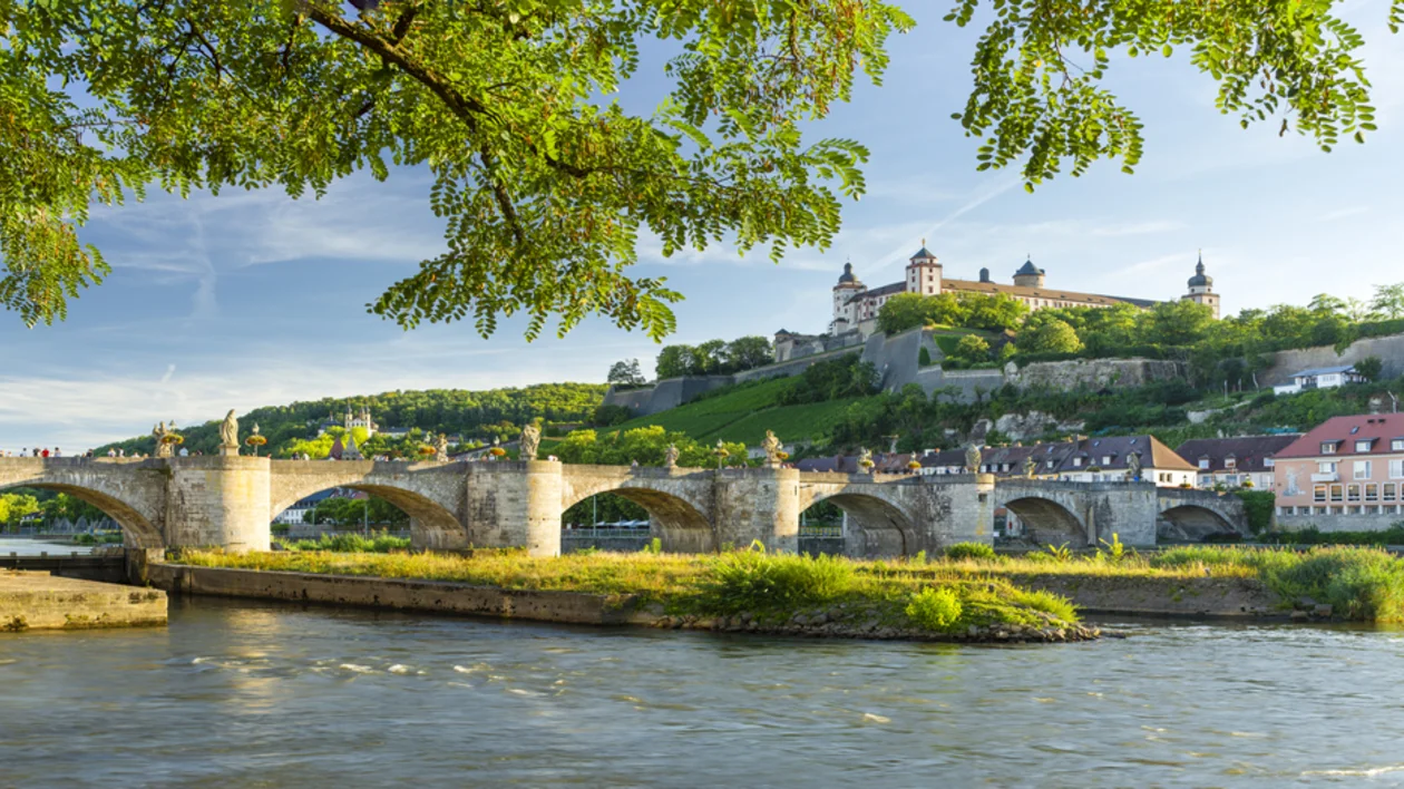 Old Main Bridge and the Marienberg Fortress in Würzburg, Germany, with vineyards and historic buildings overlooking the Main River.