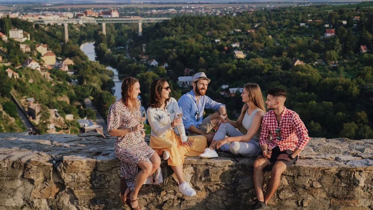 Overhead view of a group sharing wine, bread, cheese, and desserts on an outdoor terrace in Czechia.