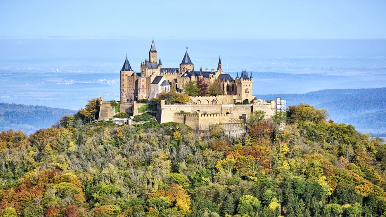 Hohenzollern Castle perched on a hill surrounded by colorful autumn foliage in Hechingen, Germany.