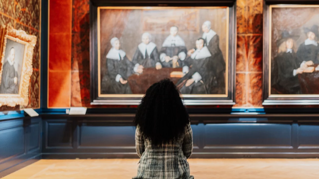 Woman seated in the Frans Hals Museum in Haarlem, Netherlands, looking at the famous painting Regentesses of the Old Men's House.