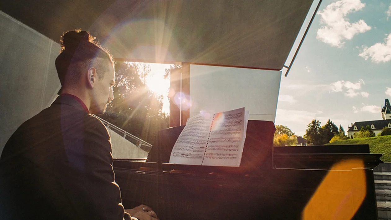A musician playing piano with sheet music in bright sunlight, representing the vibrant cultural and arts scene in Austria.