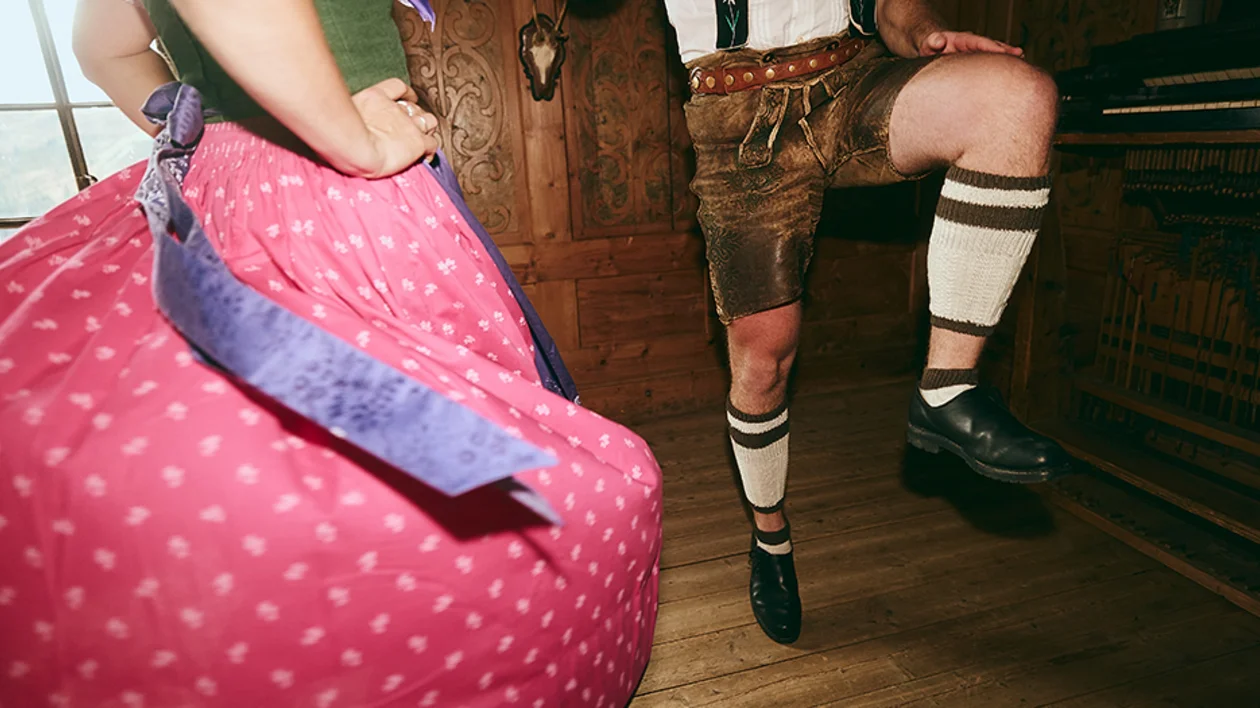 Close-up of a couple in traditional Austrian Dirndl and Lederhosen dancing indoors