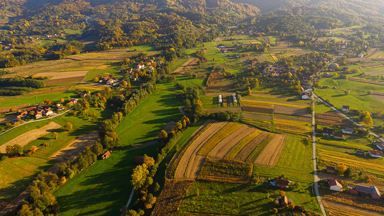 Aerial view of the rural Zagorje region in Croatia, showing patchwork green and yellow fields, rolling hills, and small villages.