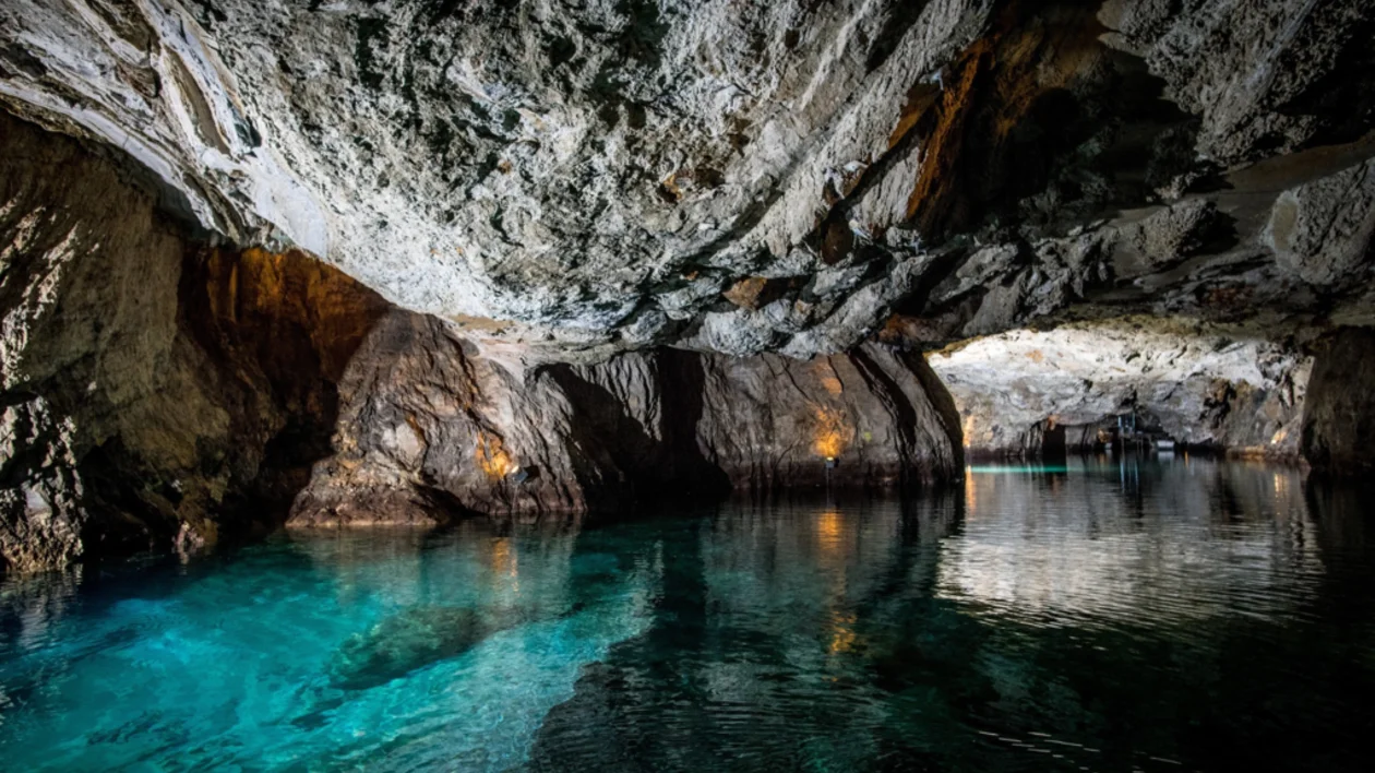 Rocky cave with turquoise water reflecting ceiling.