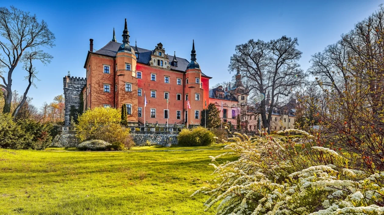 Red brick Kliczków Castle surrounded by gardens and trees in Lower Silesia, Poland.