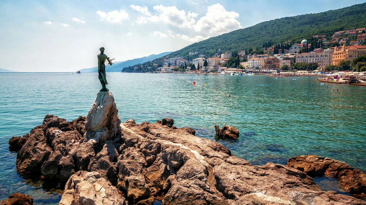 Seaside statue on rocks overlooking a coastal town