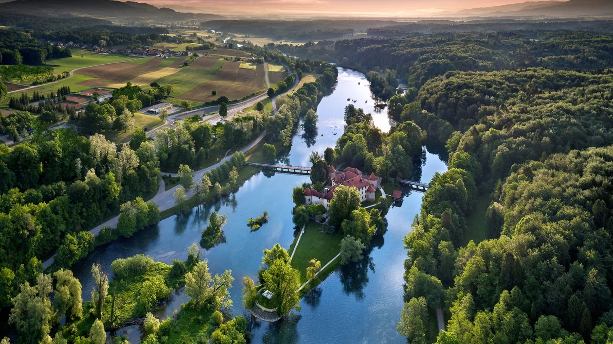 Castle on a small island surrounded by a winding river and forest