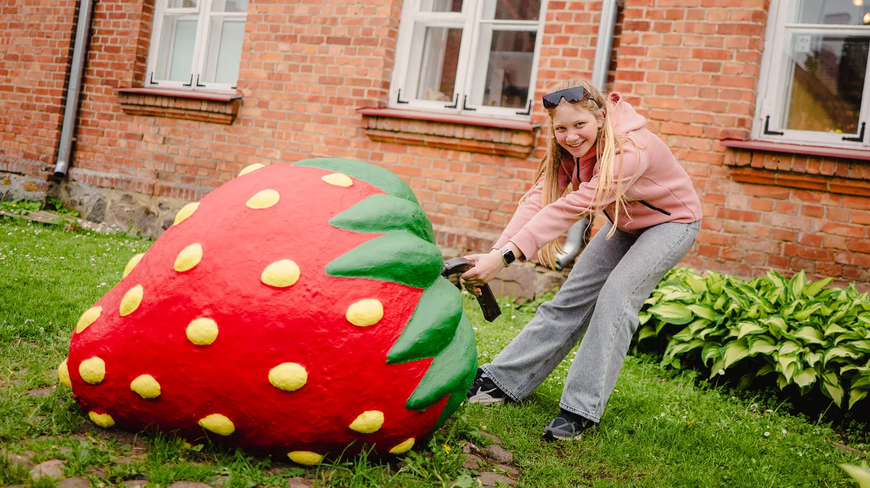 Visitor interacting with a giant strawberry sculpture in Viljandi, Estonia