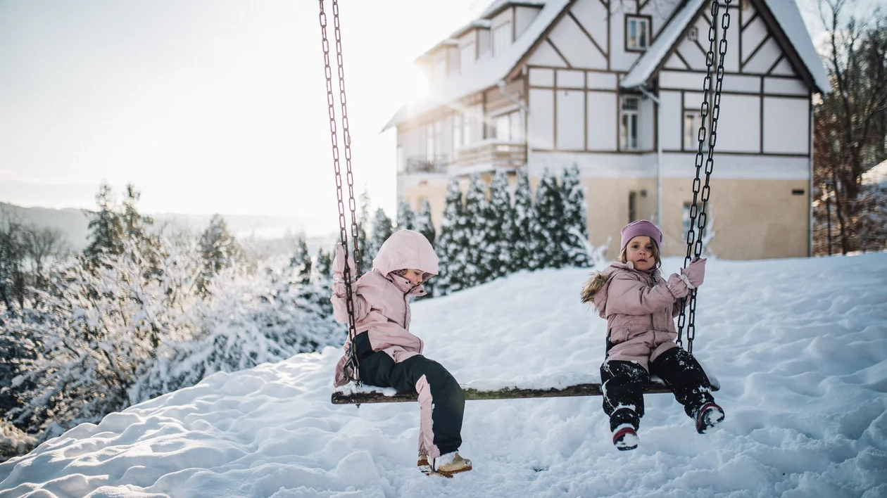 Two children playing on swings in a snowy winter landscape in Viljandi, Estonia.