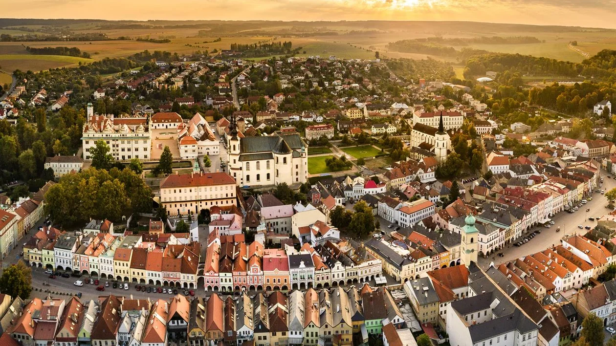 Aerial view of a town with red-roofed buildings at sunset.