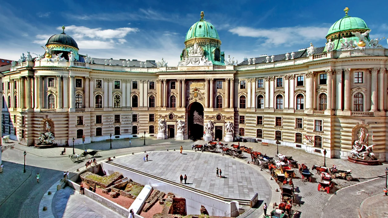 Hofburg Palace at Michaelerplatz in Vienna, with grand baroque architecture and historic horse carriages.