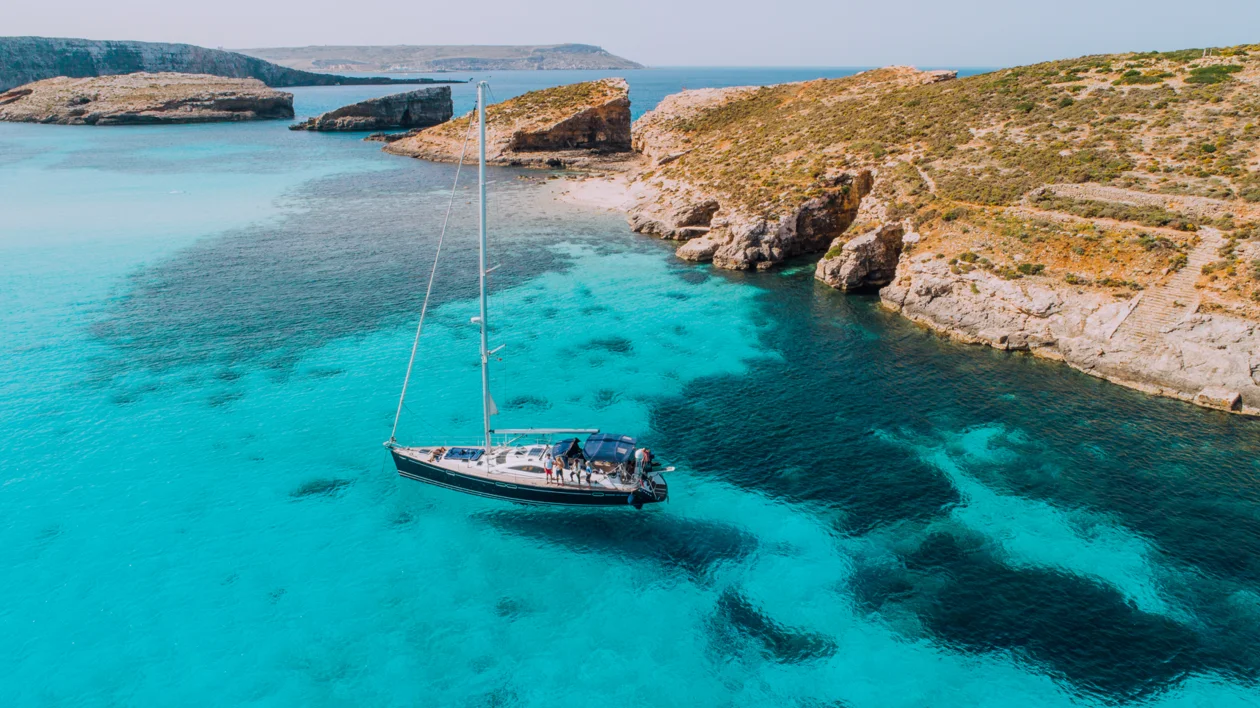 Sailboat floating on turquoise waters at the Blue Lagoon near Comino, Malta