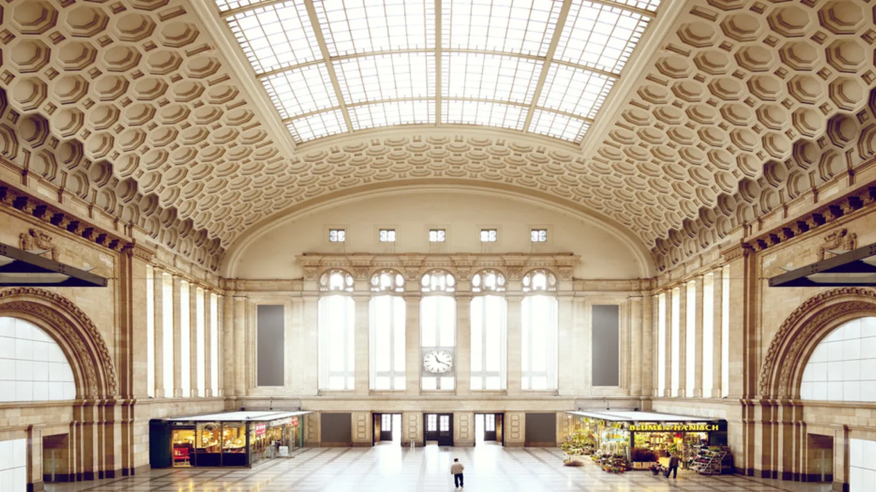 Grand hall with high arched ceiling, skylights, and two small shops on the sides.