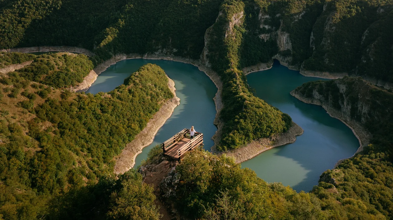 Aerial view of turquoise lakes surrounded by green cliffs and dense forest.