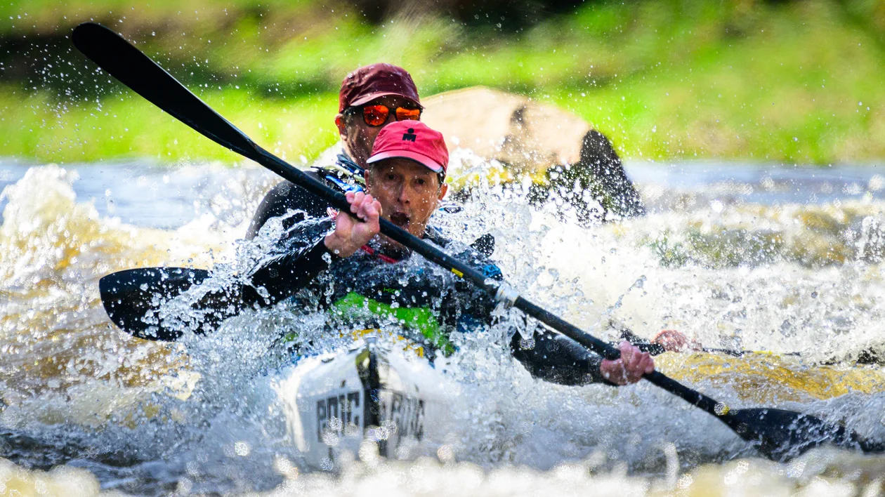 Two people kayaking through whitewater rapids, concentrating intensely.
