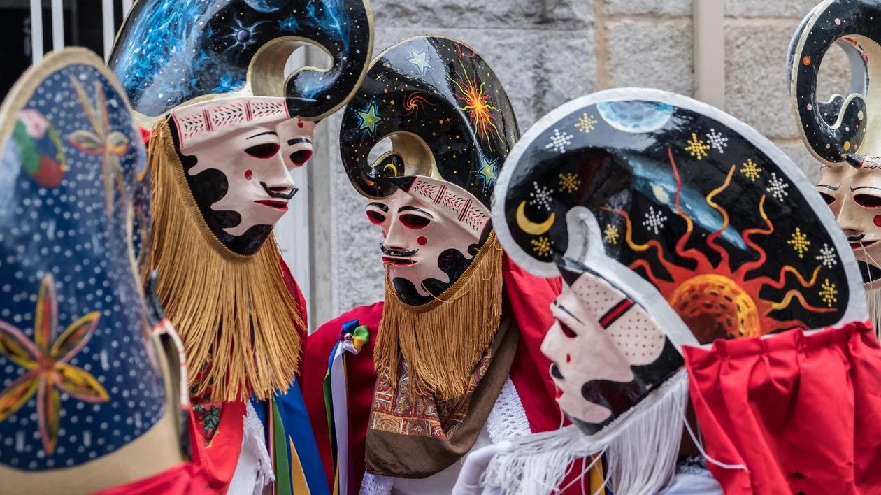 People in elaborate masks and costumes with celestial designs, standing together outdoors.