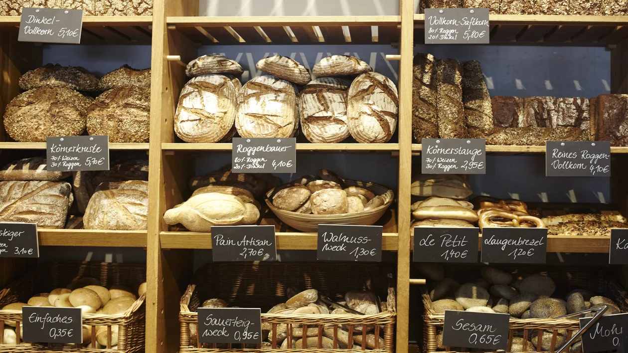 Shelves filled with various types of bread, each labeled with price tags.