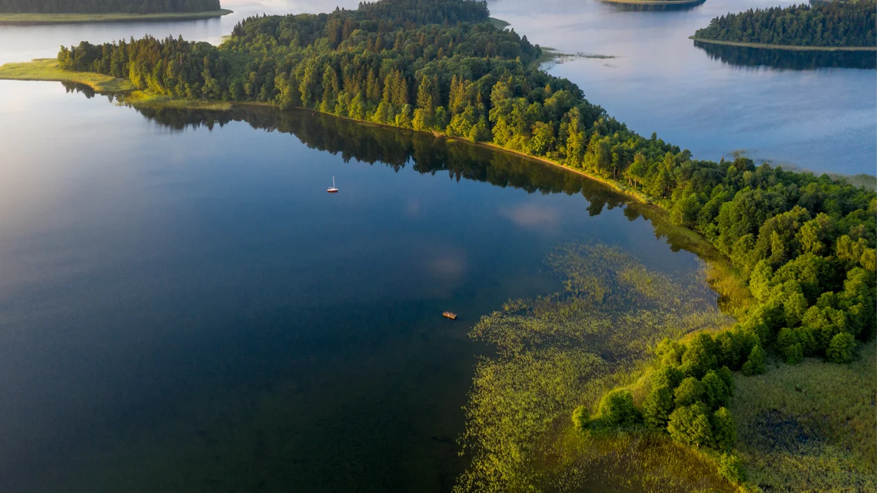 Aerial view of a green peninsula surrounded by calm blue lake water.