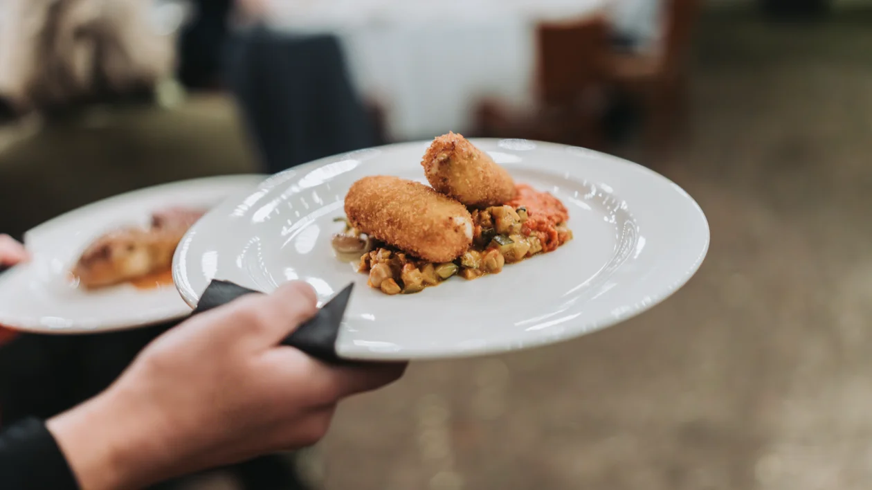 Two croquettes served on a bed of vegetables on a white plate.
