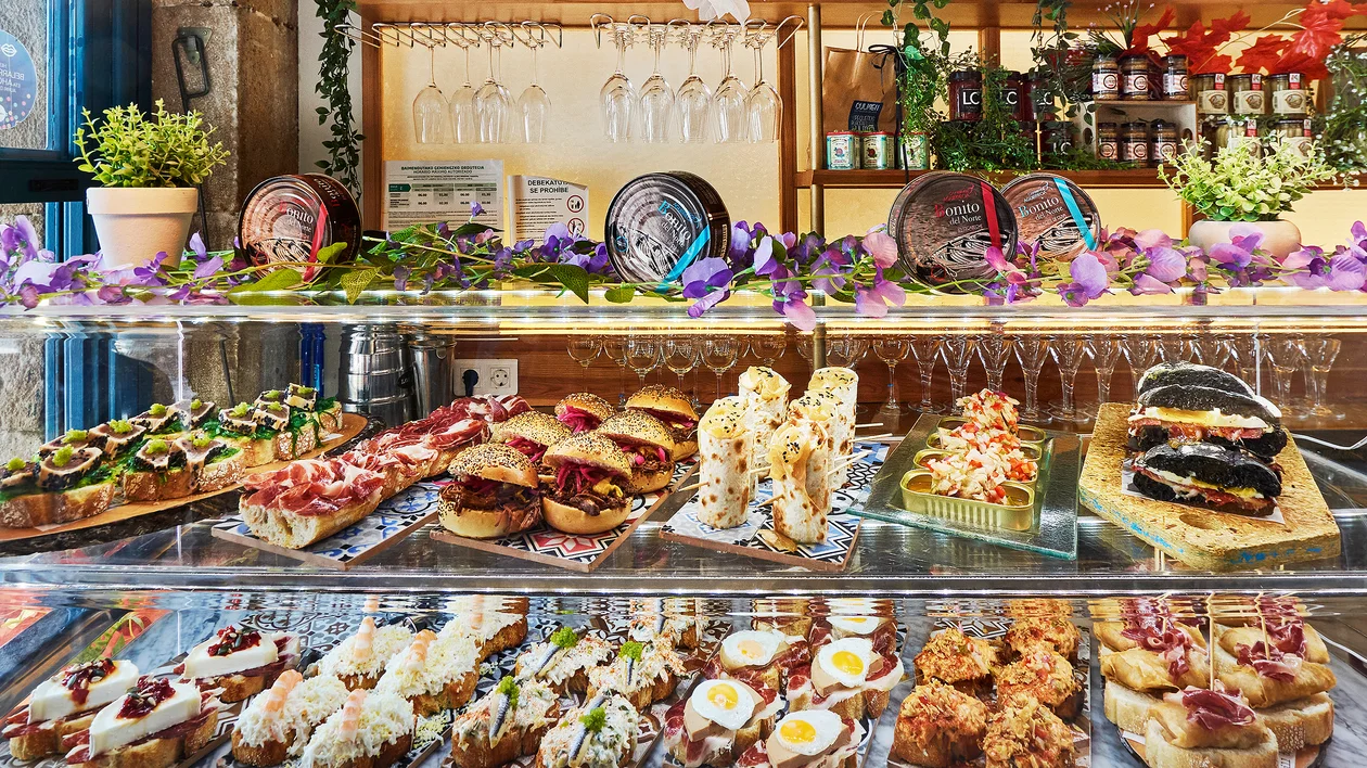 Glass display case with assorted pastries, sandwiches, and appetizers in a cafe setting.