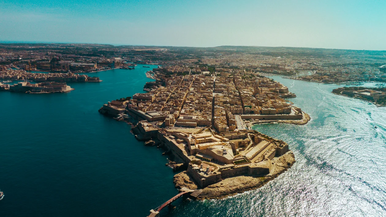 Aerial view of a coastal city peninsula surrounded by blue water under a clear sky.