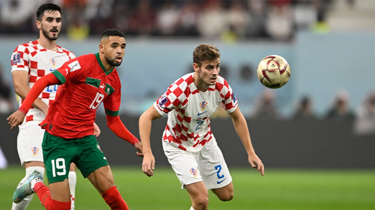 Soccer players from Morocco and Croatia chase the ball during a match.