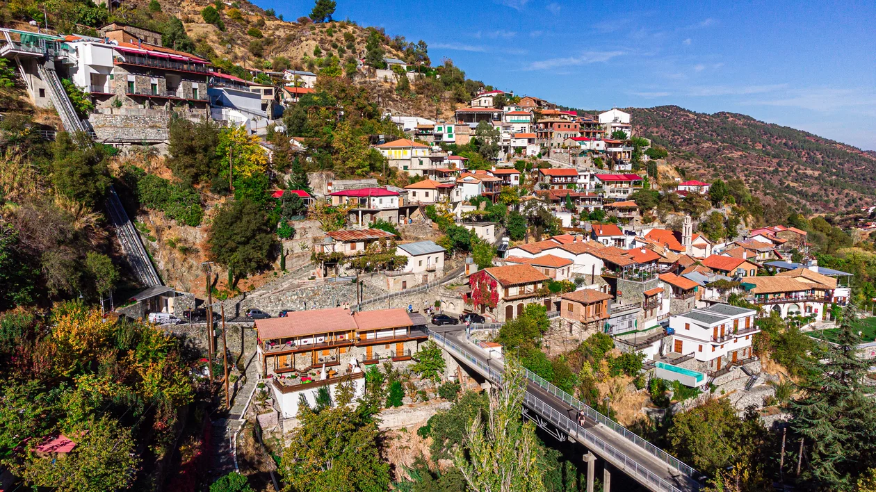 Colorful hillside village with red-tiled roofs under a clear blue sky.