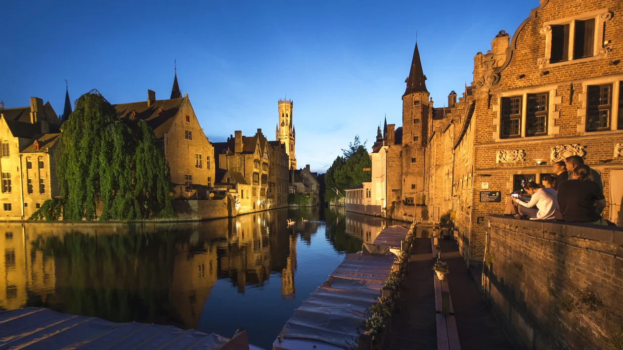 Canal lined with historic buildings at sunset, lights reflecting on the water.
