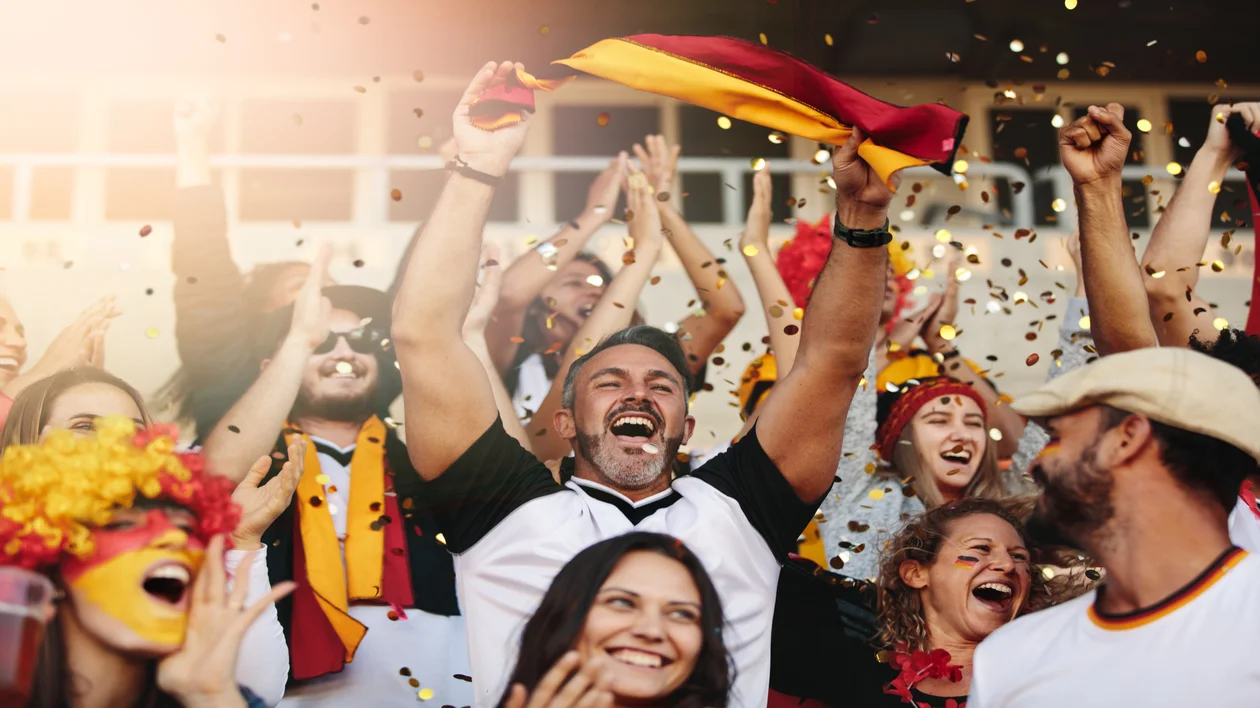 Cheering sports fans in a stadium wearing team colors and celebrating with confetti.