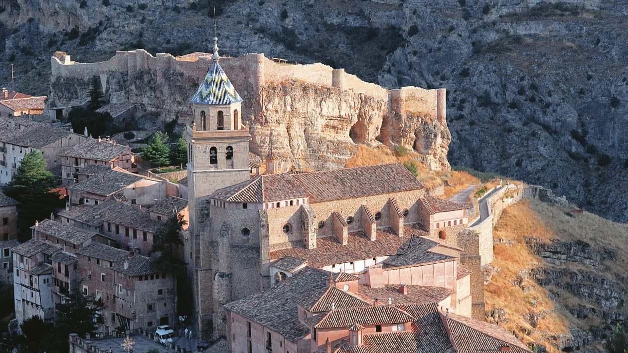 Historic church and fortress on a rocky hillside at sunset.