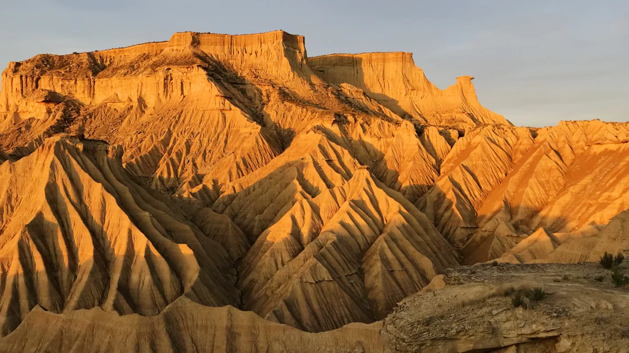 Golden rock formations with deep ridges, lit by warm evening sunlight.