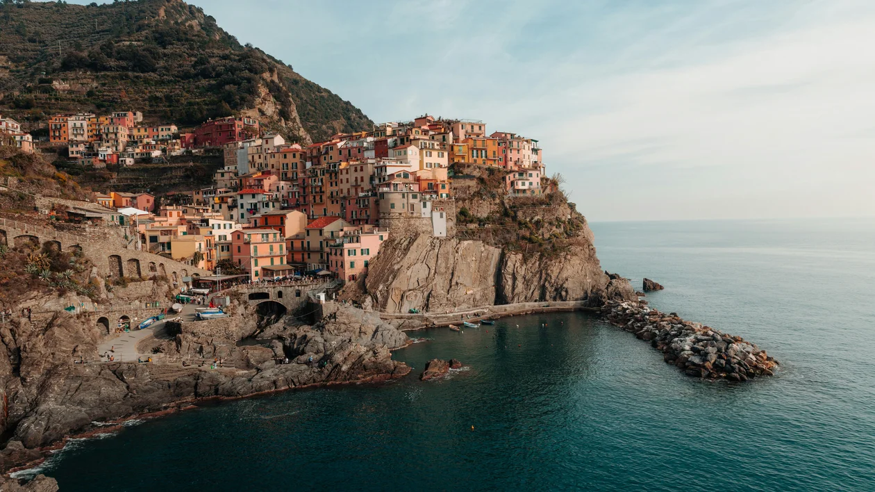 Colorful cliffside village overlooking a calm, blue sea under a clear sky.