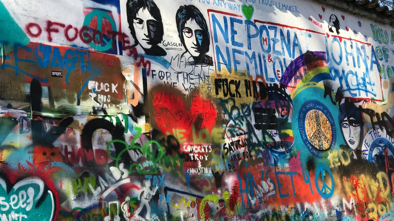 Colorful graffiti wall with portraits, peace signs, and layered messages.