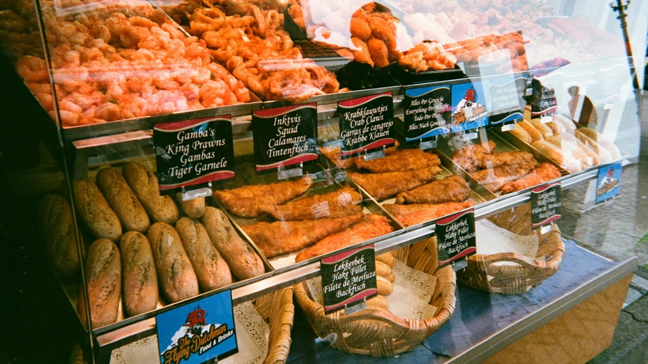 Bakery display with various breads, pastries, and handwritten labels behind glass.